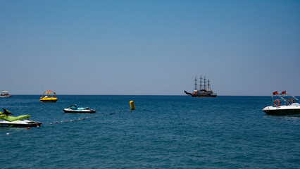 A vibrant scene of blue waters with jet skis and a pirate ship, exuding a lively summer mood. © Azur
