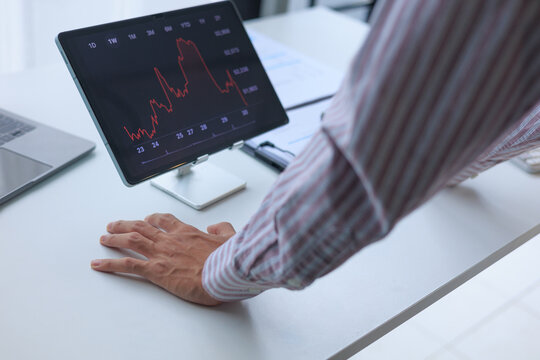 Worried businessman tracking a severe market downturn on tablet at his office desk.