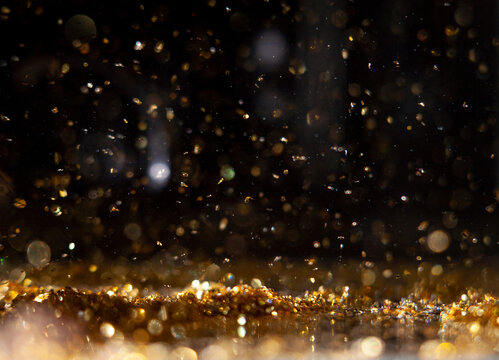 Macro photo of gold glitter sparks bokeh on black background