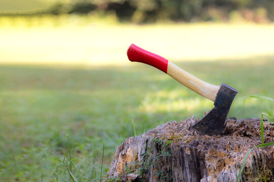 An axe stuck in a wooden chopping block at sunset. Manly chores; a lumberjack's tool.