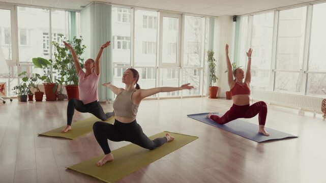 Three women stretching and practicing yoga poses on mats in a studio