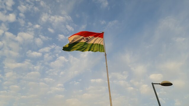 Indian national flag waving against a blue sky with soft clouds at an outdoor exhibition venue