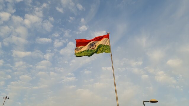 Indian national flag waving against a blue sky with soft clouds at an outdoor exhibition venue