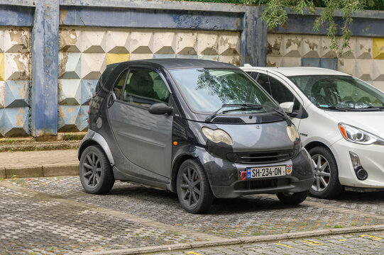August 15, 2026, Tbilisi, Georgia Commercial automotive photography of a compact grey Smart car parked on an urban cobblestone lot