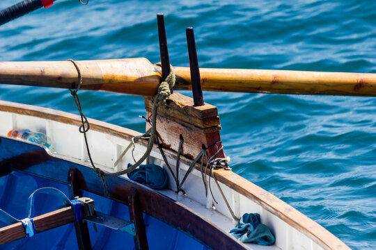 Wooden Row Boat Oarlock and Rope Close-Up Against Blue Sea Water Surface