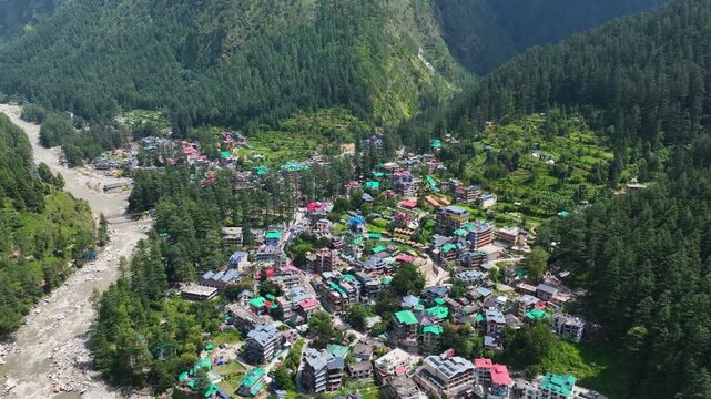 Wide drone establishing shot over the deep V-shaped Parvati Valley, contrasting the dense infrastructure of Kasol with the raw Himalayan wilderness.
