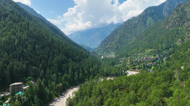Sweeping high-altitude aerial establishing shot of Parvati Valley and river near Kasol, showcasing dramatic cloud cover and pristine alpine wilderness.