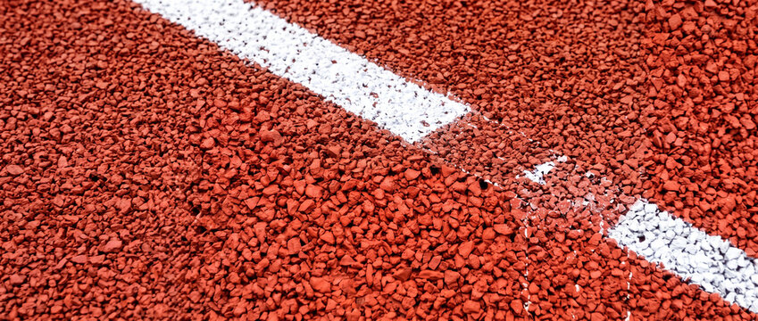 Red running track surface with white lane markings   