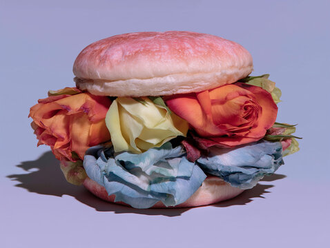 A pink burger bun surrounds a colorful arrangement of roses and petals. It is ideal for playful food campaigns and surreal social media design.
