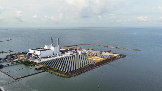 Aerial view of Maxima power plant featuring solar panels and industrial buildings situated on the waterfront in Lelystad, Flevoland, Netherlands.