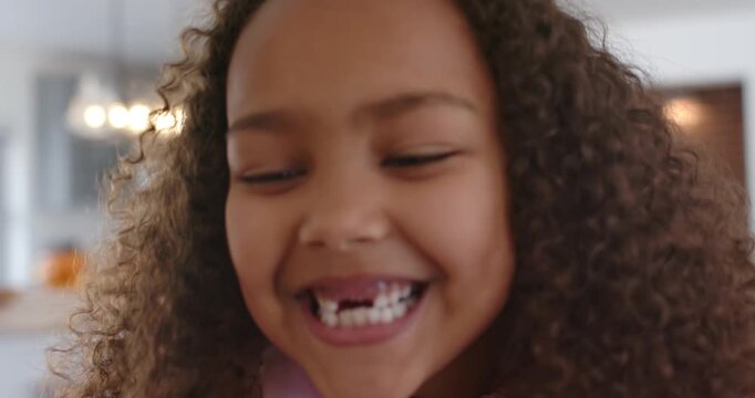 African American child in pink hoodie smiling giggling camera zooming showing gap tooth in kitchen