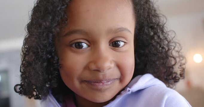 Girl child in lilac hoodie at home reacting to offscreen voice smiling leaning back revealing TV