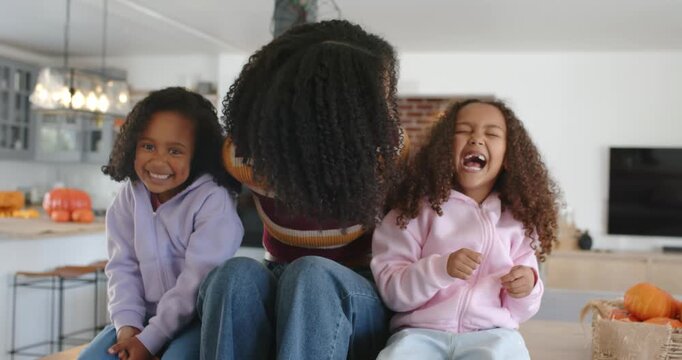 African American mom and girls sitting in kitchen, leaning, wrapping, laughing, posing by pumpkins