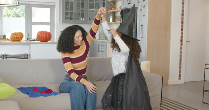 African American mom and child coming to sofa, mom placing witch hat fixing cape for Halloween