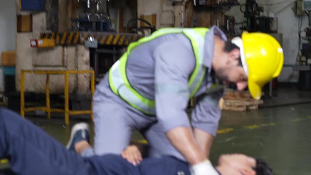Rescue worker safety gear providing first aid to injured person during industrial emergency response training beside metal stamping press, supporting injured colleague inside factory for workplace