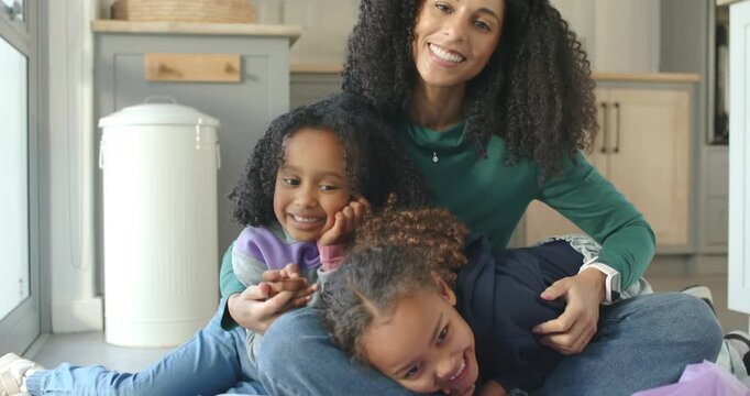 African female family sitting kitchen by window, giggling, waving at camera, clear bin visible