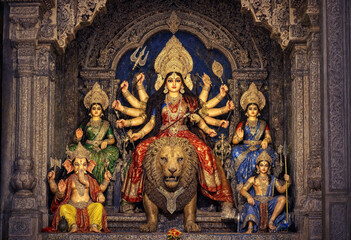 Obraz premium Colorful Hindu goddess Durga statue with lion and deities in ornate temple setting