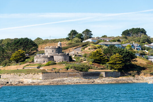 St Mawes Cornwall England UK.13.08.2026. St Mawes Castle  a stone fortification stands on a grassy hill beside the sea, with modern houses visible further up the slope