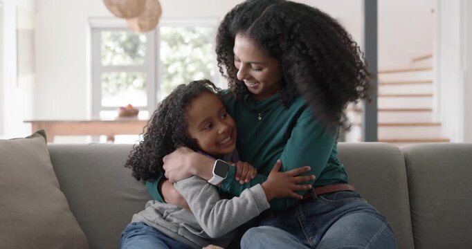 African American mother and daughter, mother initiating caring hug after exchanging looks on couch