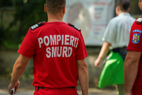 Bucharest, Romania - August 20, 2023: Back view of a Romanian firefighter paramedic in a red Pompieri SMURD uniform walking outside in bright daylight during an operation.