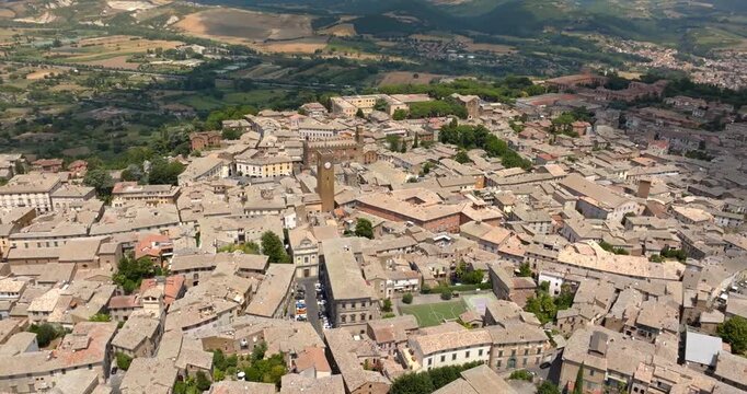 Panoramic aerial view of the historic center of Orvieto, in the province of Terni, in Umbria, Italy, with Torre del Moro, a medieval clock tower, standing above the stone buildings of the old town.