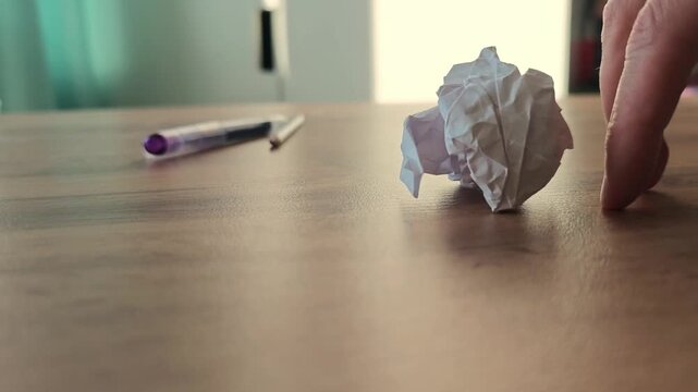 Creating a paper ball and rolling it across a table while using a pen as a guide