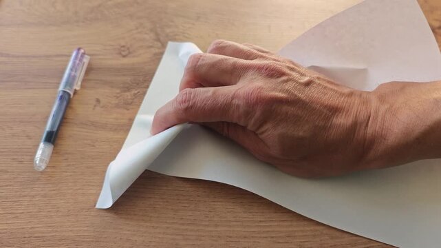 his hand nervously crumples a piece of paper on the office desk
