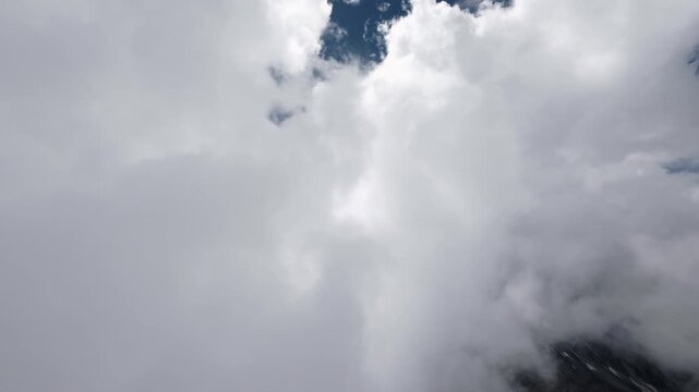 Aerial view flying through clouds above mountain peak