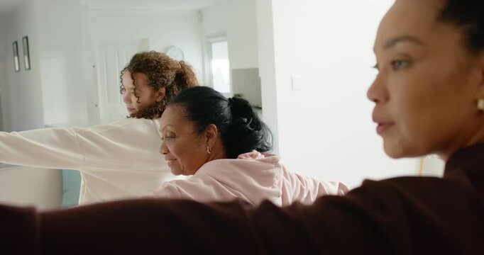 African American women with senior holding arms out, turning and smiling sharing at home in hoodies