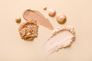 Swatches of different foundations and face powders on beige background, flat lay