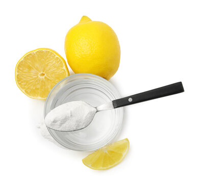 Water with baking soda in glass, spoon and lemons isolated on white, top view