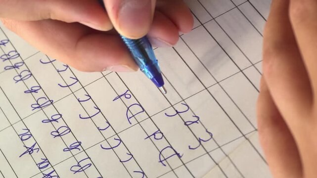 Practicing handwriting on lined paper with a blue pen in a study environment