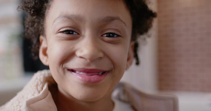 African American child reacting to camera shifting to broad grin at entry wearing tan fleece jacket