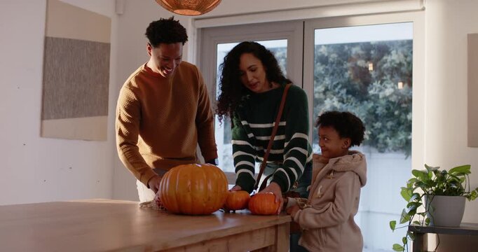 African American family placing pumpkins on wood table by sliding doors, preparing fall centerpiece