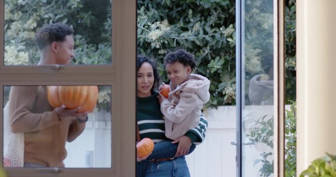 African American family entering after man opening glass door, placing pumpkins on wood table