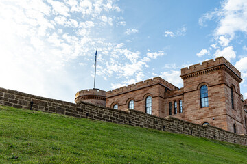 Castle with flag on grassy hill under blue sky in Inverness, Scotland, UK. © iSky Media