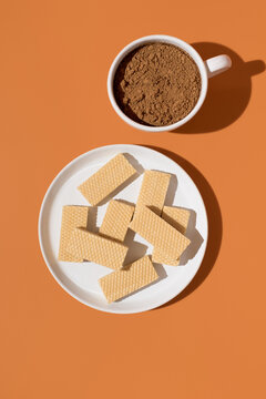 Cocoa powder and wafer cookie on orange background