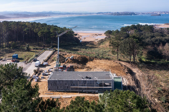 Stone-clad coastal house under construction beside beach