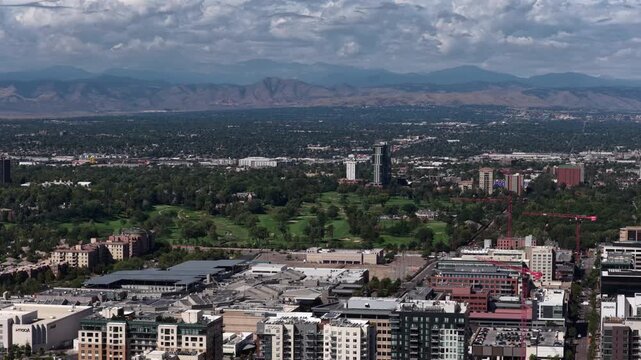 Wide aerial of Denver urban landscape with golf course and front range mountains near Cherry Creek in summer