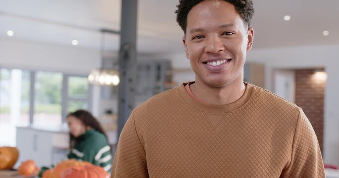 African American couple at kitchen he smiling she moving pumpkin phoning cam zooming showing grin