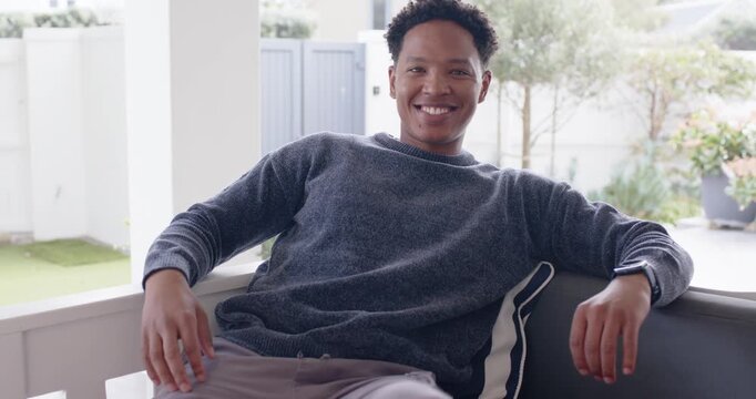 Camera receding African American man shifting smiling leaning on porch sofa with watch holding gaze