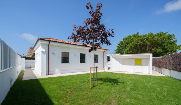 White house with lawn and modern garden structure