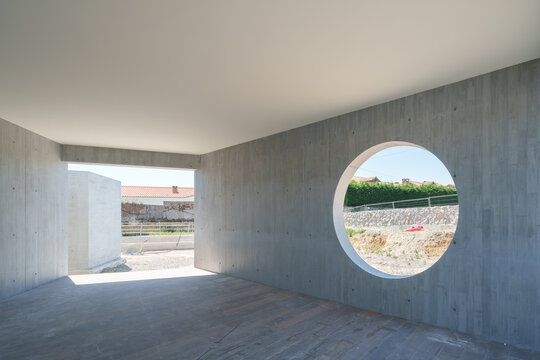 Unfinished concrete hotel interior with circular window opening