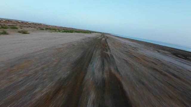 Forward tracking shot along a dirt path by water