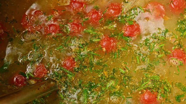 Boiling hot soup with cherry tomatoes and herbs