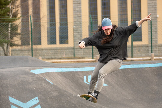 Female skateboarder ride at urban pump track skate park