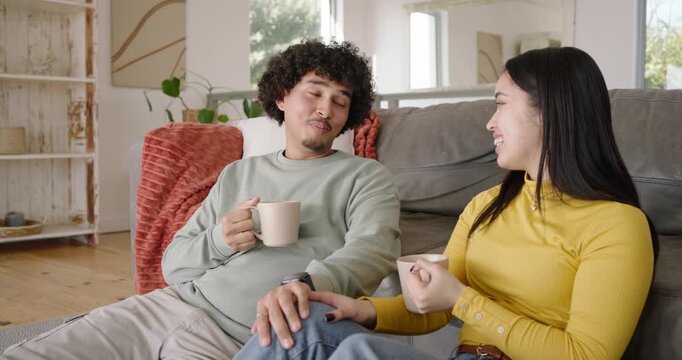 African American couple sipping pale mugs while man starting chat and connecting on gray couch