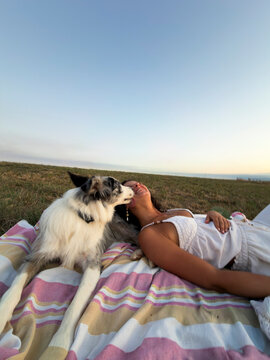 Woman relax with dog on beach blanket in summer