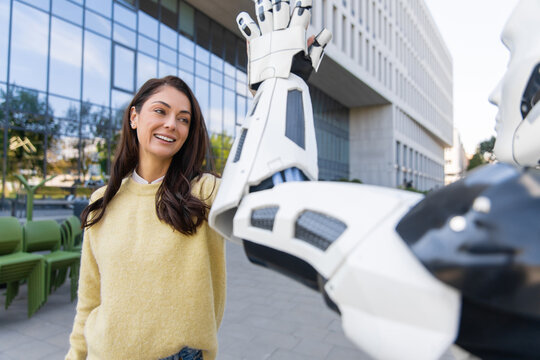 Cheerful brunette woman giving high five to android robot