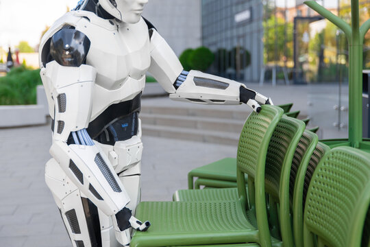 Close-up robotic assistant stacking outdoor chairs